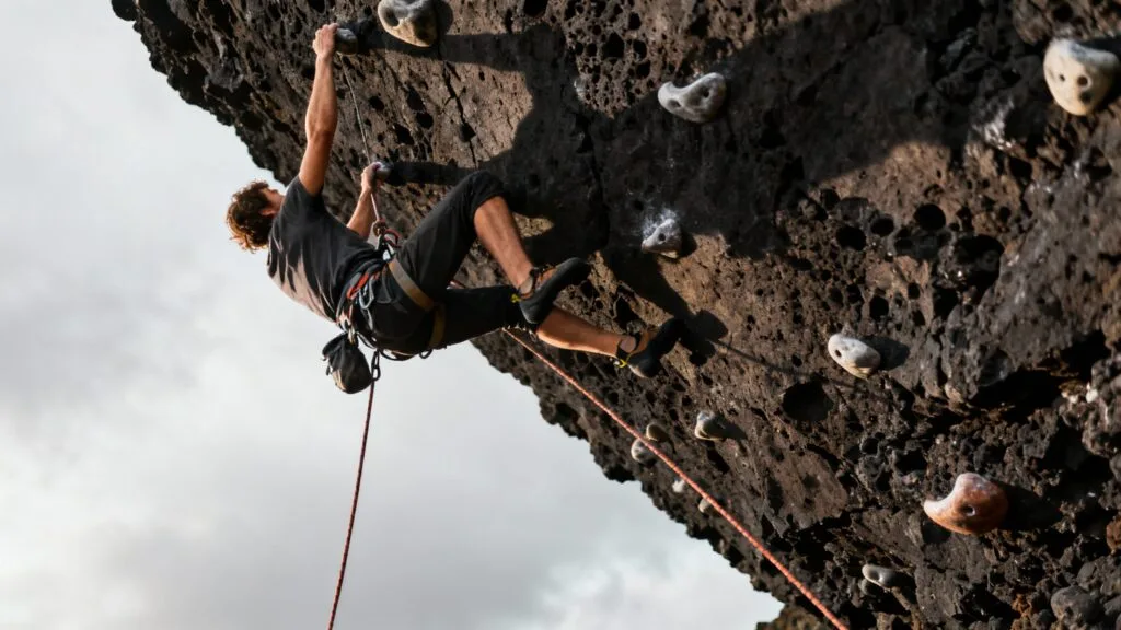Escalade sportive sur falaise sombre avec assureur
