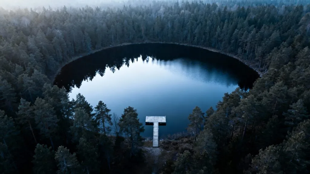 Sentier au bord d’un lac circulaire entouré de forêt dense