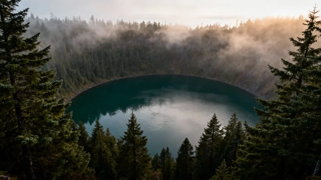 Lac volcanique sombre entouré de conifères