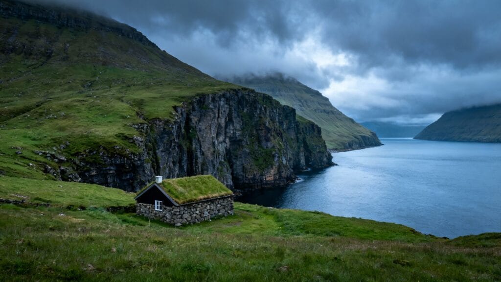 Falaises herbeuses et maison à toit végétal, mer grise
