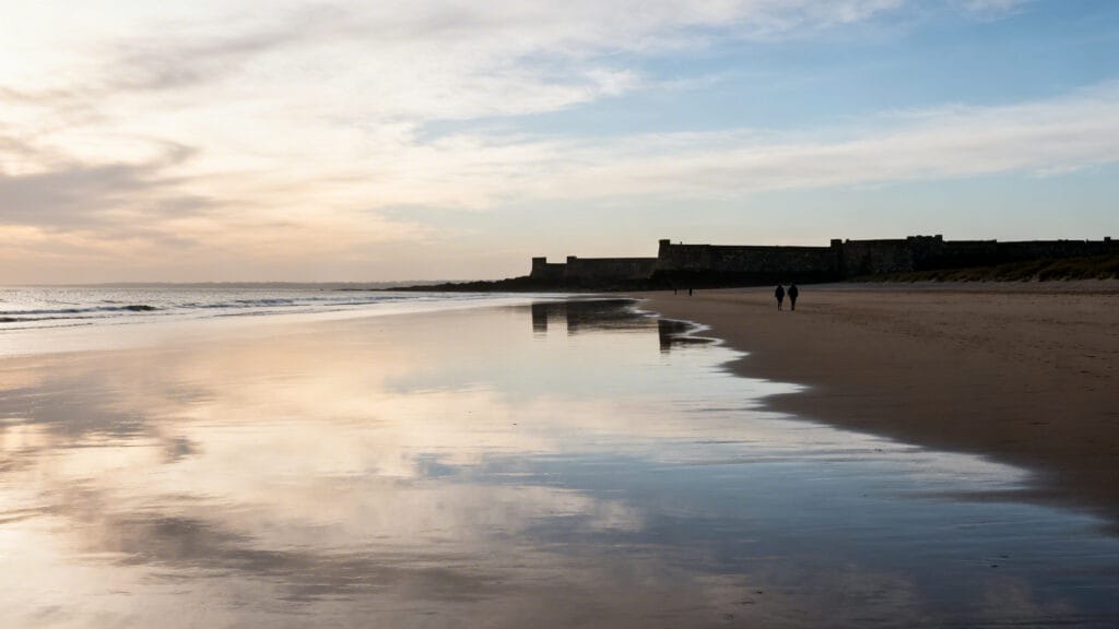 Plage vaste à marée basse avec remparts en arrière-plan