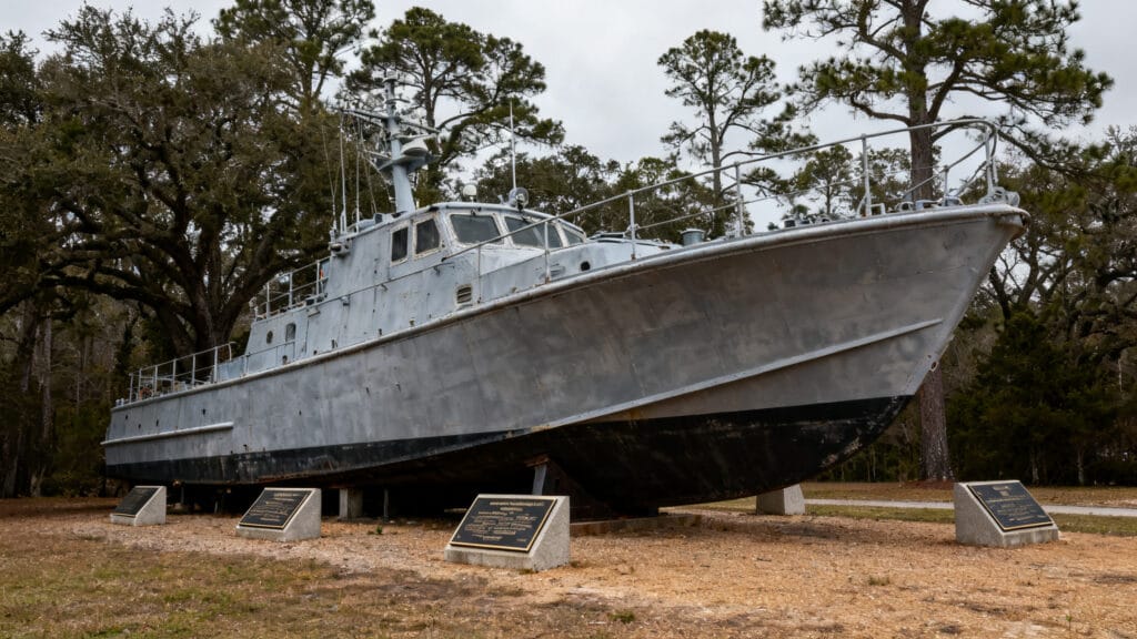 Mémorial discret avec bateau exposé et arbres autour