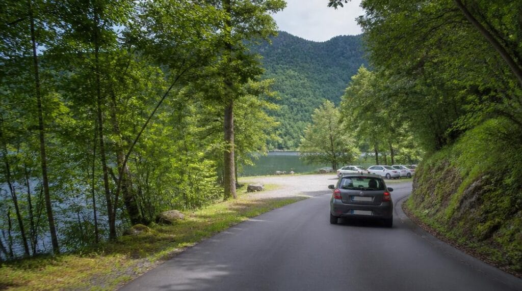 Route de montagne menant vers un parking près du lac